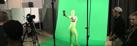 A student performing in front of a green screen